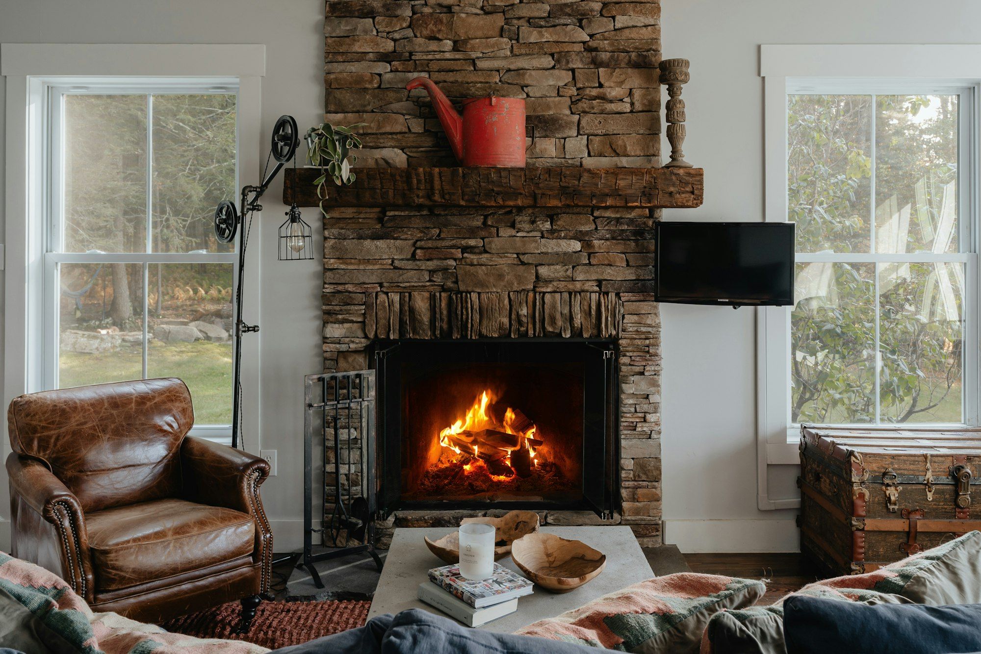 Stone fireplace with a burning fire in a sunny living room