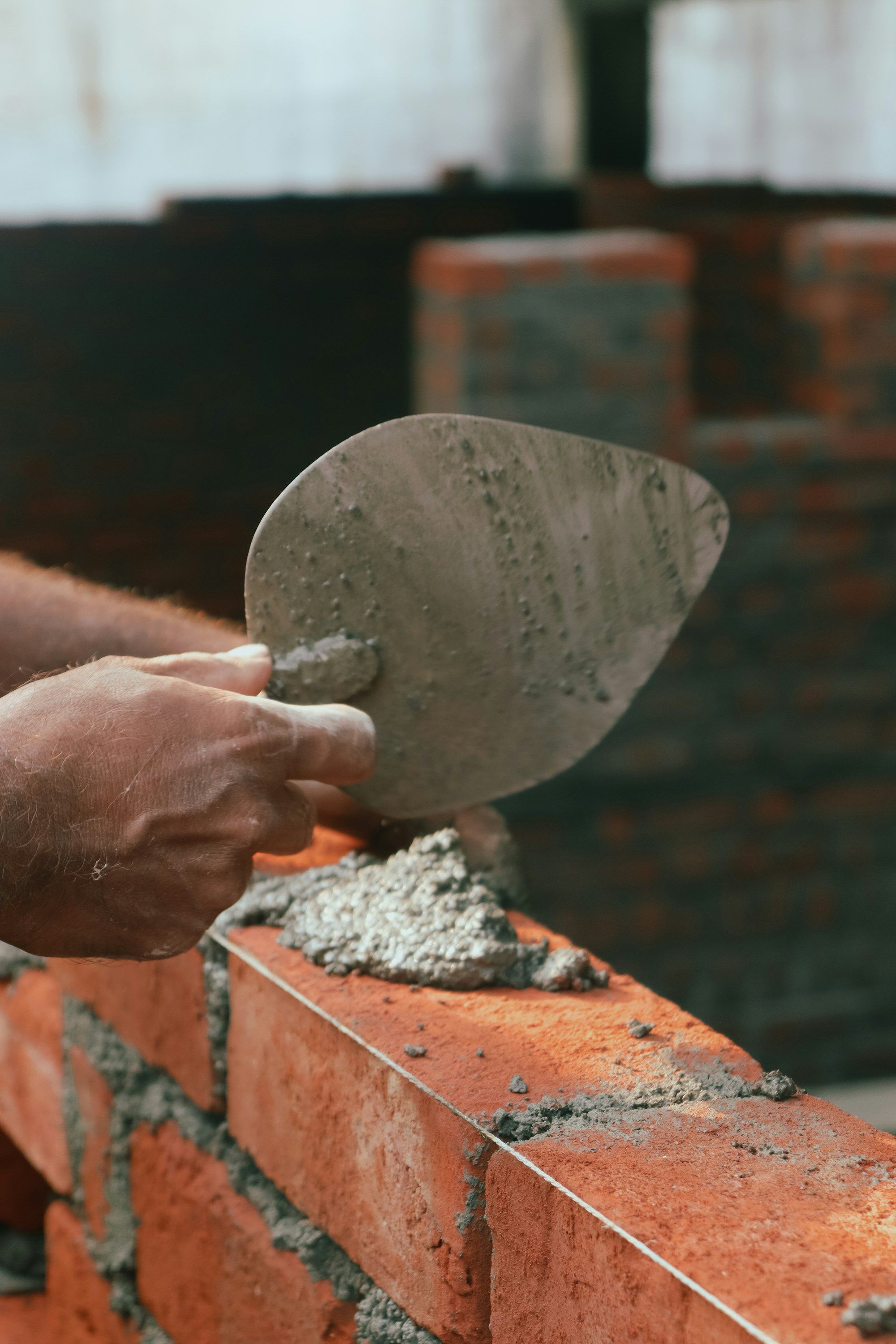 Hand spreading mortar on red bricks with a trowel