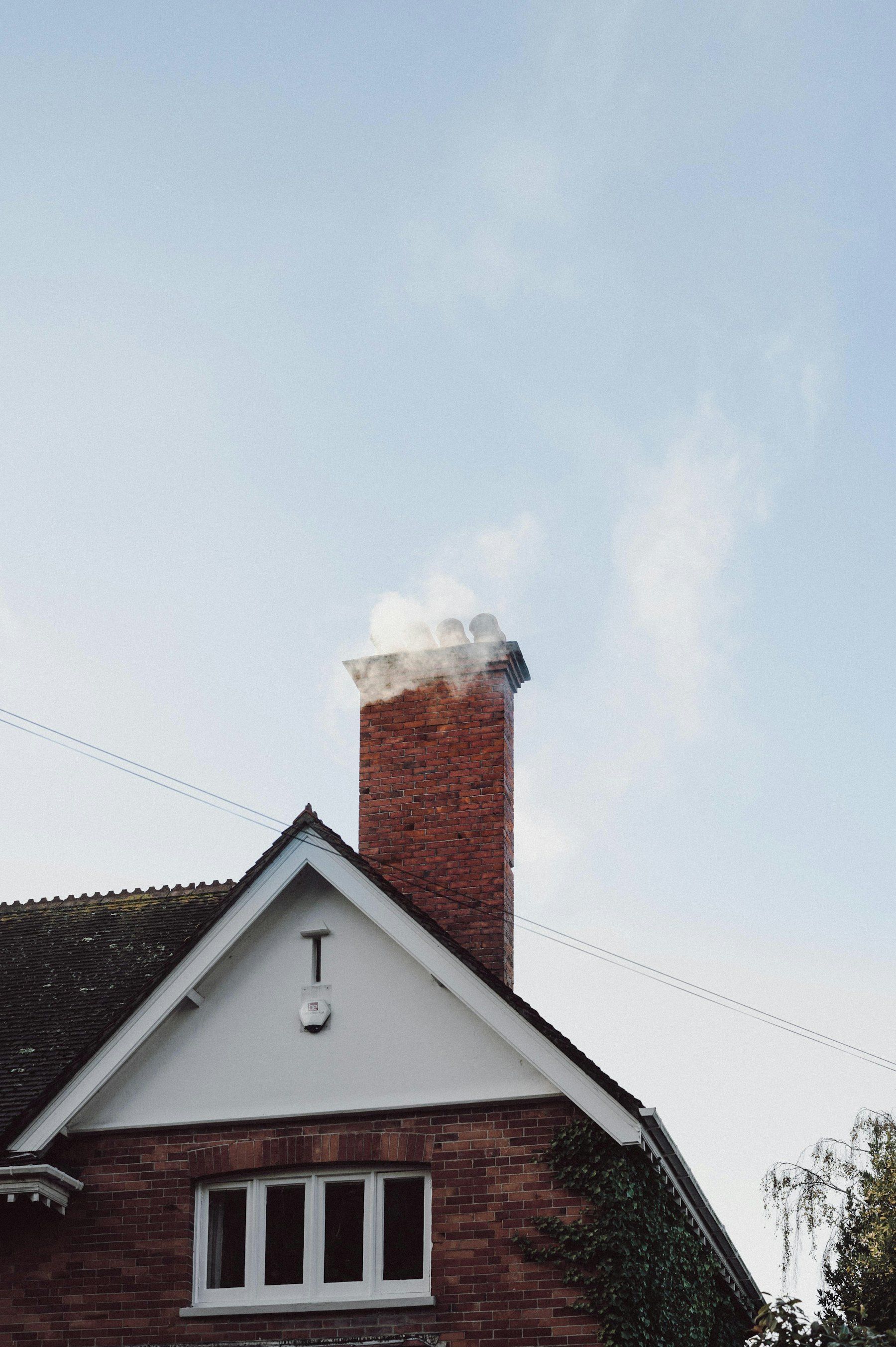 Red brick chimney rising above a gabled house roof